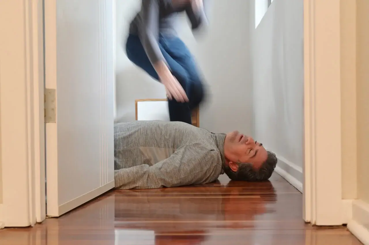Illustration montrant un homme à terre suite à un malaise, avec une personne courant pour lui porter secours.